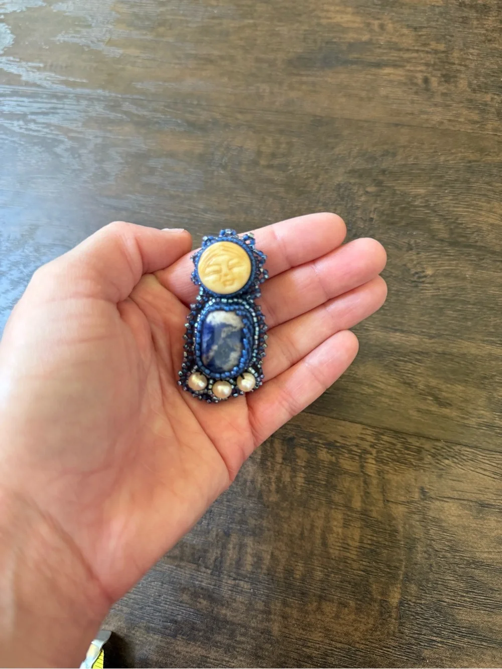 hand-beaded artisan brooch with moon face